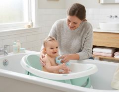 Parent gently bathing a happy infant in a baby bathtub.