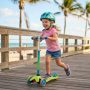 A happy child riding a scooter with an adjustable handle on a Florida sidewalk.