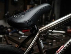Close-up of a black padded BMX seat on a custom bike frame.