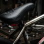 Close-up of a black padded BMX seat on a custom bike frame.